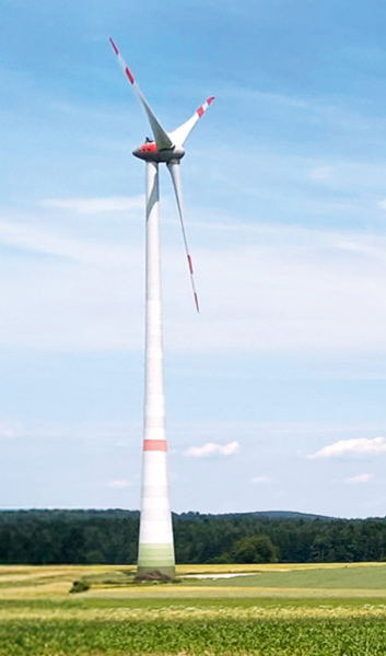 Fotografie von einer Windkraftanlage auf einer Wiese.